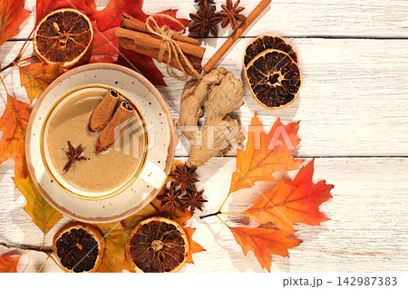 Indian masala chai with milk, ginger, anise, and cinnamon on an old wooden table with fallen autumn leaves. A traditional seasonal drink with spices, a cafe advertising card, a restaurant menu. 142987383