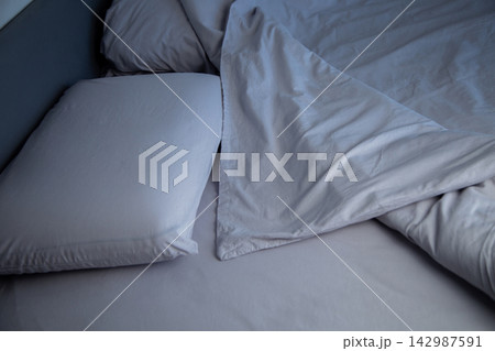 Side view of a bed with two pillows, covered with gray linens, the blanket is invitingly bent back, forming soft folds. The concept: an atmosphere of comfort and relaxation, going to bed. High quality 142987591