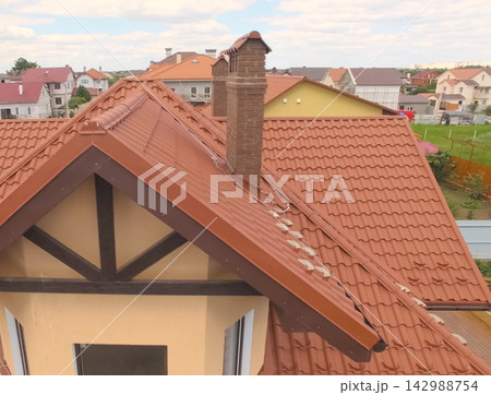 House with a new roof made of orange metal. View from above. Corrugated metal roof and metal roofing. Modern roof made of met 142988754