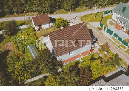 Brown metal tile on the roof of the house. Corrugated metal roof and metal roofing. Modern roof made of met 142988824