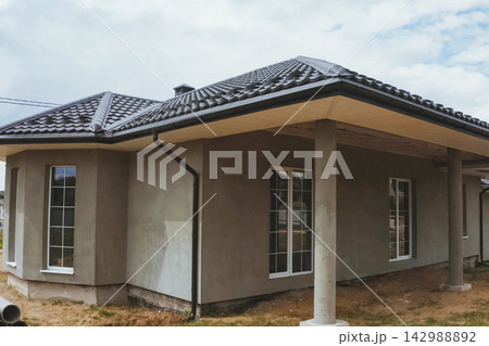 House with a brown metal roof.Corrugated metal roof and metal roofing. Modern roof made of metal. House with a brown metal roof.Corrugated metal roof and metal roofing. Modern roof made of metal. 142988892
