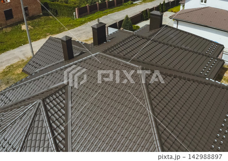 House with a brown metal roof.Corrugated metal roof and metal roofing. Modern roof made of metal. House with a brown metal roof.Corrugated metal roof and metal roofing. Modern roof made of metal. 142988897