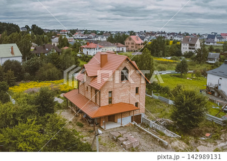 Beautiful pink brick brick house and orange roof. Corrugated metal roof and metal roofing. Modern roof made of metal. 142989131