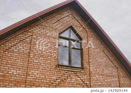 Beautiful pink brick brick house and orange roof. Corrugated metal roof and metal roofing. Modern roof made of metal. Beautiful pink brick brick house and orange roof. Corrugated metal roof and metal roofing. Modern roof made of metal. 142989144