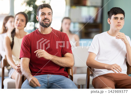 man sitting at a lecture on finance, he listens attentively and smiles man sitting at a lecture on finance, he listens attentively and smiles 142989377