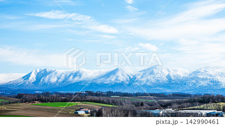 青空と十勝岳連峰が冠雪した秋の北海道美瑛町の丘の雄大な風景 青空と十勝岳連峰が冠雪した秋の北海道美瑛町の丘の雄大な風景 142990461