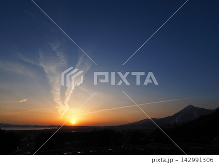 猪苗代湖の対岸に沈む夕日。シルエットの磐梯山にオレンジ色の地平線とと白い雲が青空に印象的で綺麗だ。 142991306