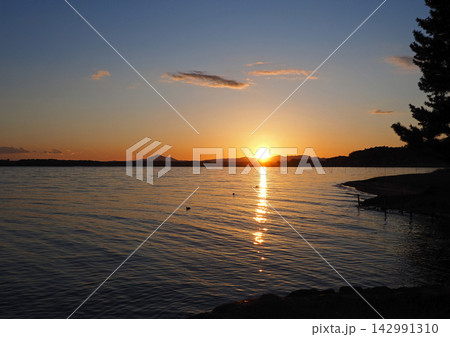 茨城県、涸沼の夕暮れ時。シルエットの筑波山にオレンジ色の夕日と雲が印象的で綺麗だ。 茨城県、涸沼の夕暮れ時。シルエットの筑波山にオレンジ色の夕日と雲が印象的で綺麗だ。 142991310