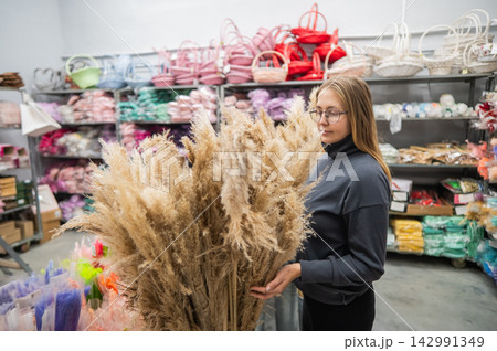 A Caucasian woman buys dried flowers at a home decor store. A Caucasian woman buys dried flowers at a home decor store. 142991349
