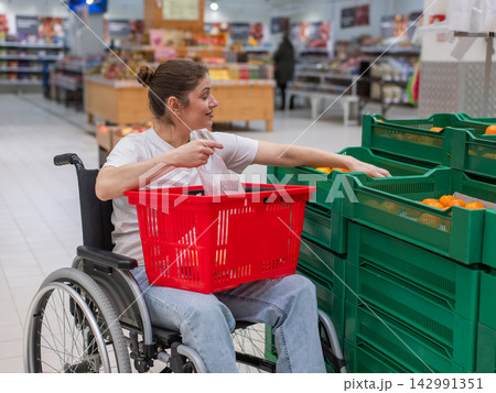 A Caucasian woman in a wheelchair buys fruit at a supermarket. A Caucasian woman in a wheelchair buys fruit at a supermarket. 142991351