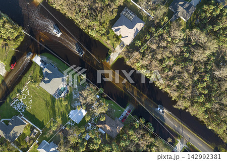 Hurricahe fainfall flooded Florida road with evacuating cars and surrounded with water houses in suburban residential area Hurricahe fainfall flooded Florida road with evacuating cars and surrounded with water houses in suburban residential area 142992381