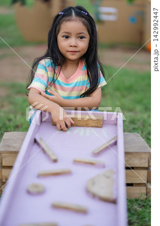 preschool child girl playing with wooden marble track game in park preschool child girl playing with wooden marble track game in park 142992447