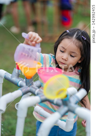 preschool child girl playing pouring water into pipe sensory play station in park preschool child girl playing pouring water into pipe sensory play station in park 142992455