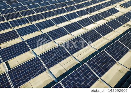 Aerial view of many photo voltaic solar panels mounted of industrial building roof. 142992905