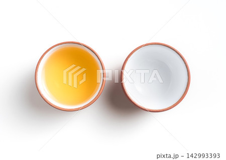 Top view of two traditional teacups one full of golden oolong tea and one empty on white background with copy space 142993393