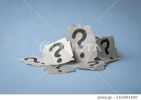Stack of torn papers with question marks. 142993400