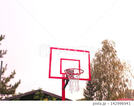 Empty red basketball hoop with net against bright sky Empty red basketball hoop with net against bright sky 142996941