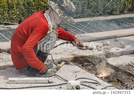 Construction Worker Welding Concrete Road Repair on Outdoor Site Construction Worker Welding Concrete Road Repair on Outdoor Site 142997355