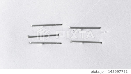 Staples pushed into a paper, metal office staple needles Staples pushed into a paper, metal office staple needles 142997751