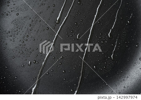 Oil drops on frying pan texture, water splash pattern on black non-stick coating Oil drops on frying pan texture, water splash pattern on black non-stick coating 142997974