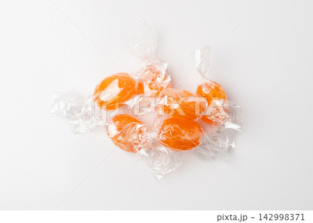 Orange hard candies isolated. Scattered lollipop pile, wrappers fruit confectionery group, round sweets 142998371