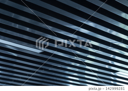 Modern interior ceiling featuring parallel metal slats, blue light reflections Modern interior ceiling featuring parallel metal slats, blue light reflections 142999281