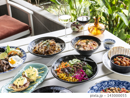 Mixed fusion western and asian lunch food spread on modern outdoor restaurant table 143000055