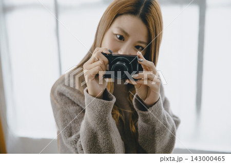 秋冬のシーンでデジタルカメラで写真を撮る美しい日本人女性 143000465