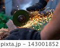 Man in protective gloves cutting metal with an angle grinder outdoors, bright sparks flying. Concept of manual labour, home workshop, DIY metalwork and work safety. 143001852