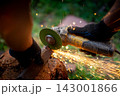 Man in protective gloves cutting metal with an angle grinder outdoors, bright sparks flying. Concept of manual labour, home workshop, DIY metalwork and work safety. 143001866