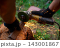 Man in protective gloves cutting metal with an angle grinder outdoors, bright sparks flying. Concept of manual labour, home workshop, DIY metalwork and work safety. 143001867