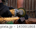 Man in protective gloves cutting metal with an angle grinder outdoors, bright sparks flying. Concept of manual labour, home workshop, DIY metalwork and work safety. 143001868