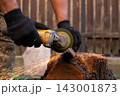 Man in protective gloves cutting metal with an angle grinder outdoors, bright sparks flying. Concept of manual labour, home workshop, DIY metalwork and work safety. 143001873