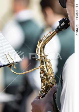 Close-Up of Musician Playing Saxophone with Sheet Music Outdoors 143001913