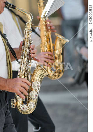 Close-up of Musicians Playing Saxophones Outdoors in Casual Setting Close-up of Musicians Playing Saxophones Outdoors in Casual Setting 143001918