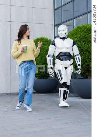 Smiling female holding coffee cup talking to humanoid robot Smiling female holding coffee cup talking to humanoid robot 143005734
