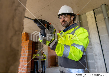 Professional worker drilling concrete wall 143005779