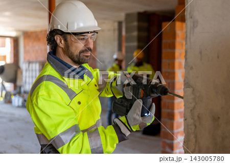 Confident builder operating hammer drill 143005780