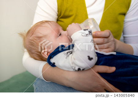 Close-up of mother bottle-feeding her cute infant baby at home. 143005840