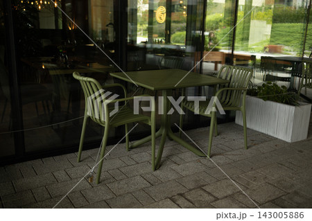 Empty outdoor restaurant cafe terrace with green metal chairs and tables Empty outdoor restaurant cafe terrace with green metal chairs and tables 143005886
