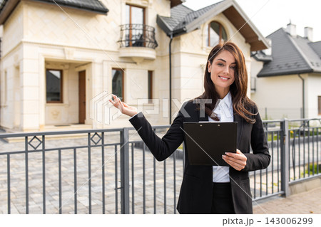 Smiling pretty real estate agent standing near the new house Smiling pretty real estate agent standing near the new house 143006299