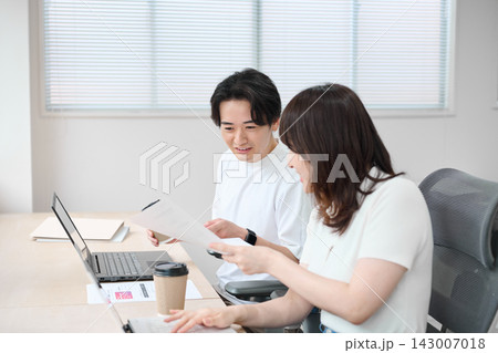 パソコンで作業をするカジュアルビジネスの男女 パソコンで作業をするカジュアルビジネスの男女 143007018