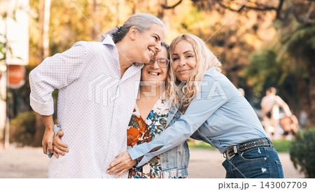 Three happy smiling women embracing in a park Three happy smiling women embracing in a park 143007709