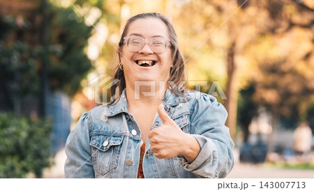 Happy woman with down syndrome showing thumbs up in a park Happy woman with down syndrome showing thumbs up in a park 143007713