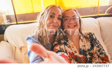 Two smiling women taking selfie on couch: 143007737