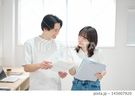 オフィスで書類をチェックする若い男女 143007920