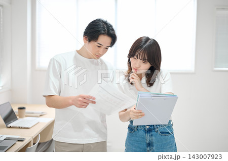 オフィスで書類をチェックする若い男女 143007923