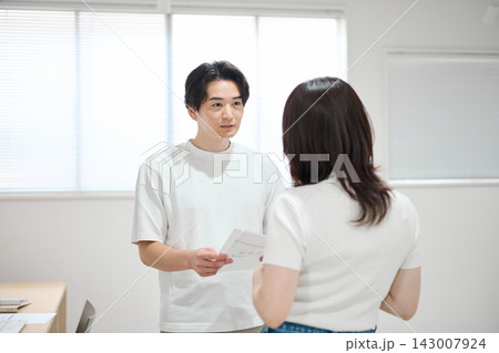 オフィスで書類をチェックする若い男女 オフィスで書類をチェックする若い男女 143007924