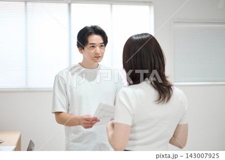 オフィスで書類をチェックする若い男女 オフィスで書類をチェックする若い男女 143007925