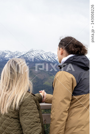 Couple enjoying panoramic mountain view together hand in hand from scenic observation platform in High Tatras. Romantic travel, emotional connection, outdoor leisure and relationship lifestyle. Couple enjoying panoramic mountain view together hand in hand from scenic observation platform in High Tatras. Romantic travel, emotional connection, outdoor leisure and relationship lifestyle. 143008226